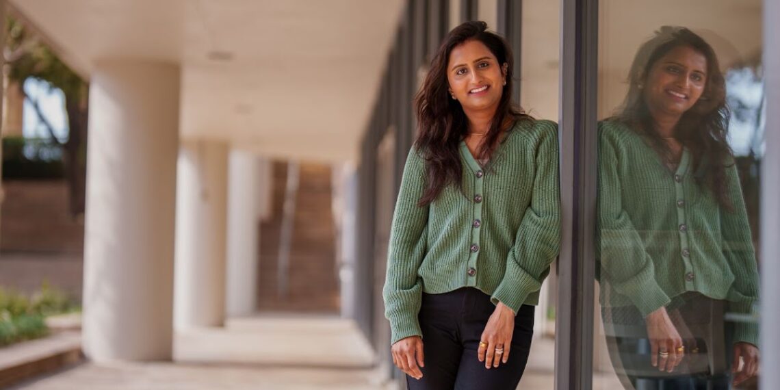 woman in green top posing beside a mirror wall
