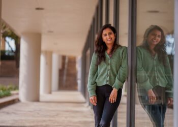 woman in green top posing beside a mirror wall